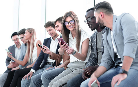 一群年轻人看着他们的智能手机屏幕工作朋友们女性男人团队办公室就业青年职业商业图片