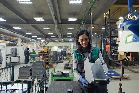 一名在现代金属工厂工作的妇女为一台新机器组装零件电脑工程控制安全工人操作员作坊女士安全帽展示图片