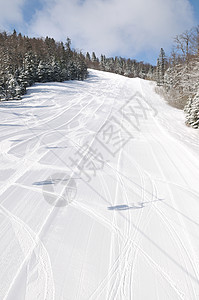 在美丽的阳光明媚的冬日 滑雪斜坡上的脚印车削森林小路大雪越野娱乐路线活动天空途径图片