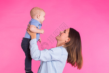 年幼快乐的母亲 带着一个有粉红背景孩子的婴儿男生喜悦女性新生微笑妈妈童年儿子乐趣家庭图片