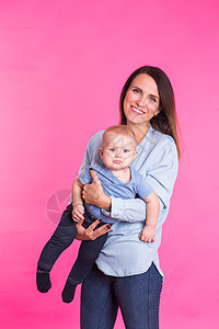 爱母亲用粉红背景和她的宝贝男孩玩耍蓝色婴儿家庭喜悦新生快乐金发男性儿子工作室图片