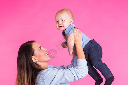 爱母亲用粉红背景和她的宝贝男孩玩耍蓝色乐趣男生喜悦几个月女士孩子微笑儿子情感图片