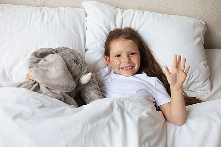 可爱的小女孩醒来 躺在床上和玩具大象睡在一起枕头就寝婴儿时间毯子童年小憩卧室孩子女性图片