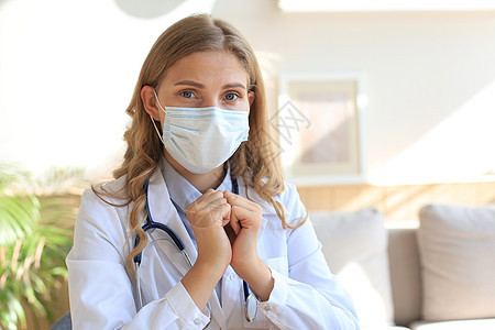 身戴面具的女医生坐在医务室时祈祷图片