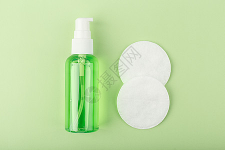 在浅绿色背景的两个棉垫旁边贴上皮肤清洗泡沫或凝胶的近皮净化泡沫或凝胶图片