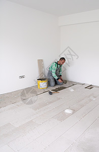 在地板上安装陶瓷木效应瓦板的工人控制板胶水房间瓦工压板材料职场男人房子木地板图片