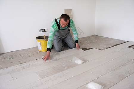 在地板上安装陶瓷木效应瓦板的工人职场公寓工作男人地面材料木匠瓦工控制板承包商图片