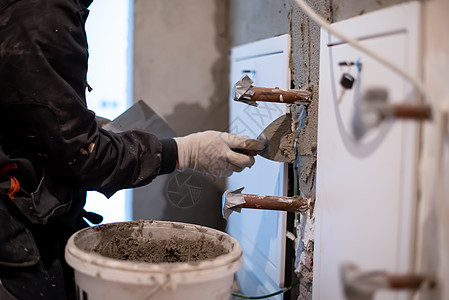 工人用混凝土在墙上打石膏石工脚手架材料水泥建筑学房子工具砂浆贸易平台图片