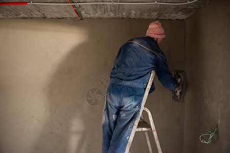工人用混凝土在墙上打石膏脚手架工具材料泥水匠建筑水泥承包商石工高度维修图片
