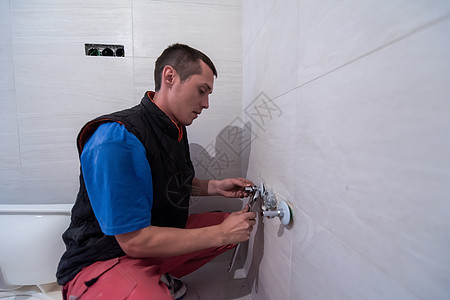 在卫生间工作的专业水管工金属淋浴男性浴室脸盆建筑房子管道工人扳手图片