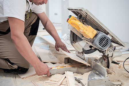 男子用电环锯锯切割压板地板木板木匠木头控制板男性建筑工作木地板安装工具承包商图片