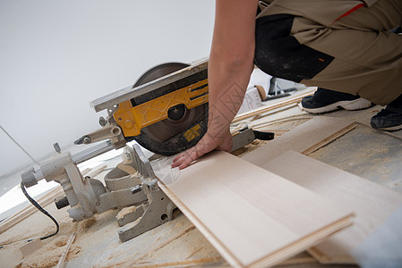 男子用电环锯锯切割压板地板木板磁带锤子木头硬木木匠工作控制板木地板地面装修图片