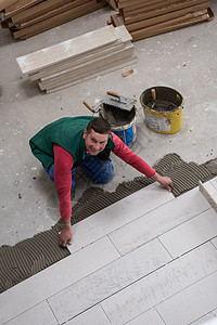 在地板上安装陶瓷木效应瓦板的工人控制板锤子瓦工工具制品建筑学压板承包商木板职场图片