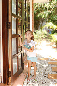 小美国女孩站在门边 外面有玩具 背景是棕榈树图片