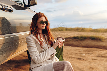 坐在田地椅子上的美女 戴着黑色眼镜 在车场附近无休止的摄影太阳镜倾斜幸福旅行成人车辆汽车自由女士图片