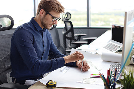 一个英俊的男建筑师 在他的办公室里设计一个设计衬衫技术阶层战略商务解决方案地点工作蓝图组织图片