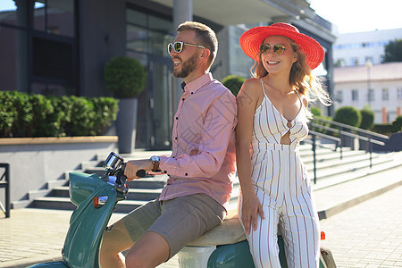 年轻漂亮的夫妇骑着摩托车 冒险和度假的概念 笑声男人旅行花束花朵恋人城市乐趣驾驶运输自行车图片