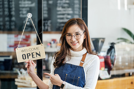 初创商店 小企业主站着在接待处展示标志 供在冠状病毒情况开始出现后前来使用店内服务的顾客使用围裙零售安全饭馆职业柜台服务员暴发女图片