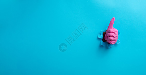 粉红色家庭橡皮手套棒 从撕破的洞里出来 显示一个手势 好 举起拇指蓝色女性协议手臂情感粉色女士卫生家务手指图片