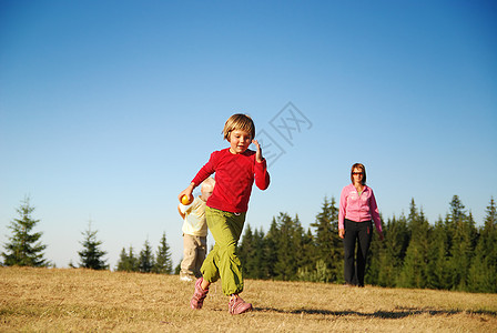 母亲和孩子在外面玩得开心场地成人晴天乐趣家庭微笑生活天空男生跑步图片