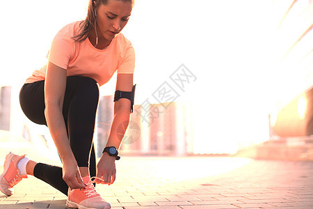年轻健身迷人的运动型女跑步者将鞋带绑在她准备跑步的运动鞋上赛跑者鞋类损失公园重量成人运动女性领带运动员背景图片