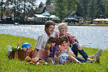 幸福的家庭在野外野餐中一起玩成人水果公园夫妻女性女士男人假期娱乐孩子图片