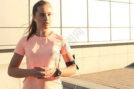 城市日落或日出时 年轻有吸引力的体育健身女青年站在户外赛跑者街道程序运动跑步行动手机音乐播放器运动员精神图片