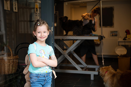 可爱的小女孩站在美容院前 为动物举行美容会沙龙卫生工具微调器女性小狗宠物商业美容师修剪图片