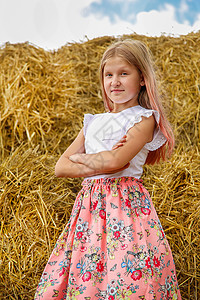 一个穿着粉红裙子的金发女学生 在炎热的夏日 爬上一大堆稻草农业太阳草垛青年女孩女士小麦快乐草地长发图片