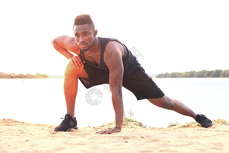 身穿运动服的非洲男子暖和起来 在海滩室外肖像上 在日落或日出时身体福利训练混血儿体力人士护理热身活动体操图片