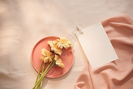盘子里的鲜花和黄色背景的布料和纸张粉色婚礼织物信封正方形邀请函花朵问候语空白艺术图片