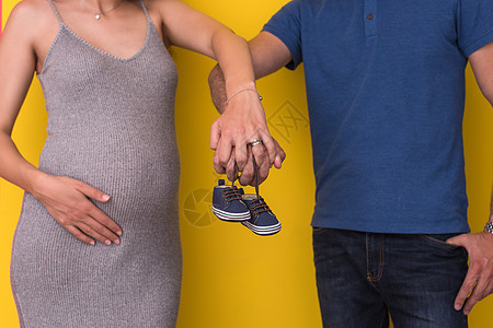 持有新生儿婴儿鞋的夫妇成人母性婴儿怀孕母亲亲热家庭幸福父母父亲图片