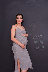 在黑粉笔板前对孕妇的肖像身体快乐成人婴儿妈妈女性冒充怀孕生活女士图片