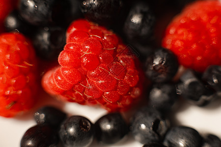 在明亮的阳光下躺在桌子上一块白色陶瓷板里 里面躺着许多多汁新鲜而成熟的红草莓浆果宏观收成覆盆子园艺食物团体小吃花园果味果园图片