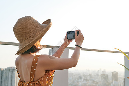 亚洲女人用专业摄影机拍照 年轻摄影师 自然光线照女士快乐游客城市旅游女孩照片旅行相机女性图片