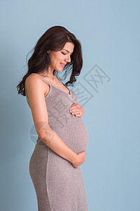 蓝色背景对孕妇的纵向照像父母妈妈怀孕女性女孩母亲生活母性腹部婴儿图片