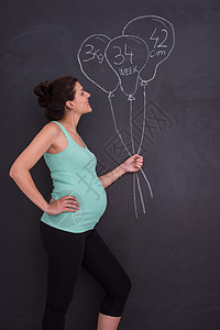在黑粉笔板前对孕妇的肖像工作室生活父母女士婴儿身体妈妈快乐母性成人图片