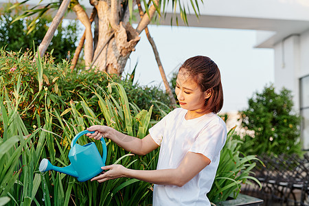 穿着白衬衫的亚洲年轻女子 在花园里浇水植物商业园艺园丁女性阳台爱好喷涂绿色女士图片