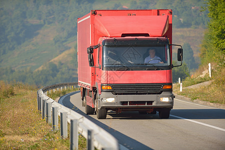 在沥青路上驾驶的红色卡车船运货车拖运草地蓝色交通汽车车辆货运沥青图片