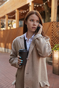 穿着时髦的米花大衣的女人 用智能手机打来电话 喝咖啡城市头发街道女士呼唤女性褐色饮料公共场所咖啡图片