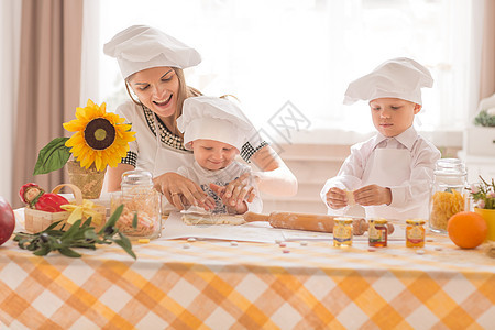 快乐的妈妈和她的孩子 在厨房做饼干图片