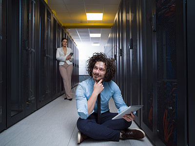 青年技术员在服务器上共同工作数据库人员男性女性备份数据走廊团队中心技术图片