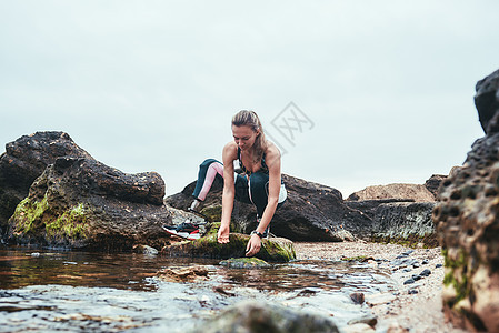 身穿运动服 假腿从河里手中取水的女子图片