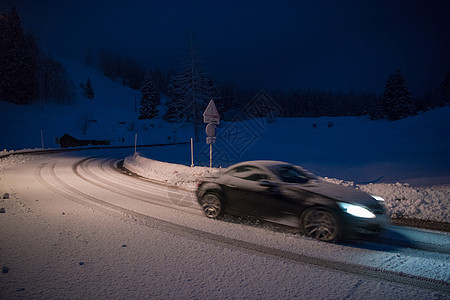 晚上在雪上危险路上驾驶汽车季节薄片国家蓝色头灯天空旅行曲线运动暴风雪图片