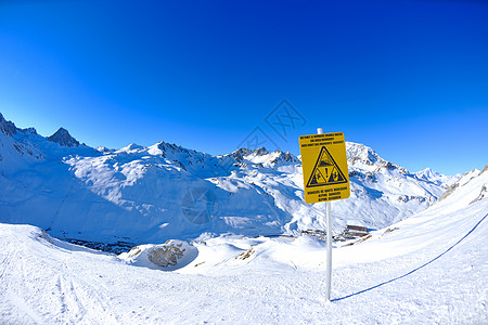 在高山的标志板上签字 冬天下雪危险木板太阳阳光蓝色帮助全景冻结顶峰天空图片