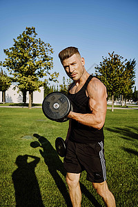 在公园培训生活方式中穿黑色T恤的运动男子娱乐男人女性训练哑铃培训师晴天运动员肌肉锻炼图片