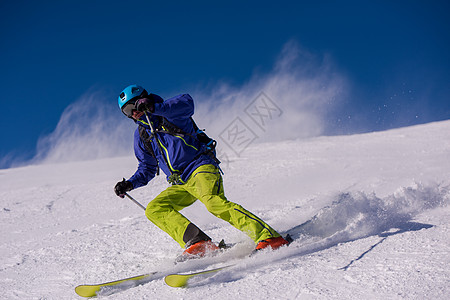 滑雪者在下坡时玩得开心滑雪速度行动衣服空气晴天山腰娱乐男人竞赛图片