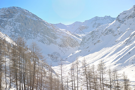 冬天下雪的高山高山蓝色首脑岩石环境太阳爬坡假期顶峰运动滑雪图片