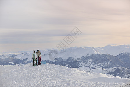 滑雪车的夫妇在山顶木板运动男性夫妻浪漫日出天空男人衣服质量图片