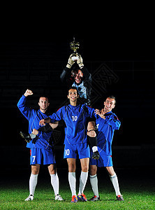 足球运动员们庆祝胜利的胜利冠军游戏团体绿色杯子庆典体育场运动球员男人图片